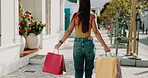 Back, shopping and walking with woman in sidewalk in city for consumerism, buying or purchase. Bags, carry and retail sale with customer person outdoor to search for bargain, deal or discount