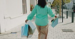 Back, woman and shopping with bags in city for travel, retail purchase and customer experience. Hands, female shopper and commute outdoor with package for bargain, commercial spree and boutique sales