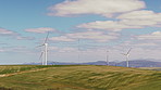 Wind turbine, renewable energy or grass field with blue sky for economic development in nature. Windmill, outdoor sustainability or eco friendly environment with alternative resource in countryside