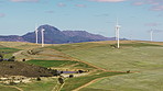 Drone, wind turbine and renewable energy on landscape on field, sky or clouds for eco friendly electricity. Hill, mountains and windmill at farm for sustainability, power and farmland in countryside