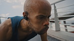 Man, push ups and earphones in city for fitness with strength training, audio and listen to music on bridge. African person, exercise and outdoor with streaming service, strong and workout in town
