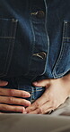 Hands, indigestion and stomach with person in home living room for bowel symptoms of ibs condition. Abdomen, cramps and tummy ache with woman in apartment for discomfort, gut health or pain relief
