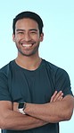 Crossed arms, fitness and face of man in studio with confidence for muscles, strength and health. Happy, portrait and person with pride for gym membership, exercise and workout on blue background