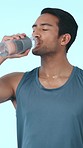 Fitness, drinking water and face of man in studio for training, athlete and wellness. Health, exercise and bottle with person on blue background for electrolytes hydration, cardio and sports rest