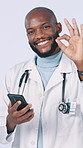 Phone, studio and face of doctor with okay sign for patient report, insurance and online results for telehealth. Healthcare, emoji and black man on smartphone for good news on white background