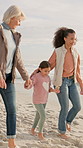 Beach, grandmother and child holding hands with mom, bonding or talk with seashell on holiday. Grandma, girl and walk with mama by ocean for love, smile and generations with interracial family