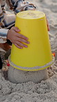 Beach, hands and child with bucket for sandcastle, play and relax on summer vacation. Kid, toys and holiday with soil at coast in nature for building game, development and travel on tropical island