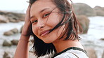Wellness, windy or Asian woman at seaside with face, positive attitude or chill on weekend break. Peace, portrait or female person at beach with fresh air, good mood or outdoor getaway in New Zealand