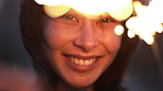 Face, woman and sparkler for celebration, series and laughing on new year at night on vacation. Fireworks, portrait and excited person at party, funny and happiness on holiday for getaway outdoor