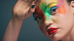 Face, art and woman with makeup in studio, gray background or colorful fantasy for beauty aesthetic. Serious, person and self expression with red lipstick, rainbow paint and cosmetics for wellness
