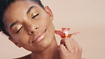 Beauty, face and flower with woman on studio background for cosmetics or dermatology. Natural, organic wellness or vegan skincare and model person with orchid plant for satisfaction or sustainability