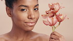 Face, skincare and black woman with orchid, beauty aesthetic and antioxidants for antiaging benefits. Person, flower and natural cosmetic for dermatology, wellness and self care on studio background.
