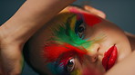 Face, paint and woman with rainbow makeup, studio background and beauty aesthetic with fantasy glow. Serious, person and self expression with red lipstick, art and creative with cosmetics and color