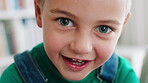 Face, relax and boy with smile by bookshelf in home, learning and academic growth in literacy education. Portrait, happy and child by book collection in apartment, curiosity and knowledge development