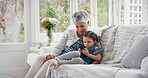 Grandmother, phone and relax with girl on sofa in home living room together for bonding or visit. App, gaming and granddaughter streaming in apartment with senior woman for break, love or learning