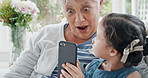Grandmother, phone and surprise with girl on sofa in home living room for bonding, love or visit. App, gaming or wow with child granddaughter and shocked old woman in apartment together for streaming