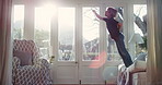 Superhero, child and jumping on couch, freedom and boy with energy in living room and laugh in home. Kid, happiness and fly on air in lounge, play and fantasy game on weekend, flare or fun in house