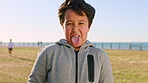 Beach, funny face and tongue out with boy outdoor in summer for travel, trip or vacation. Crazy, humor and joke with silly child on grass lawn at coast for comedy, goofy or playful expression