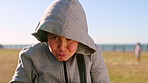 Beach, funny face and hoodie with boy child outdoor in summer for travel, trip or vacation. Crazy, humor and squint with silly kid on grass lawn at coast for comedy, goofy or playful expression