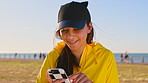 Teenager, girl and earphones at park with phone, social media update and listening to music on holiday. Happy, gen z person and audio tech outdoor with beach vacation, mobile app and online radio.