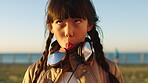 Beach, funny face and holiday with Asian girl outdoor in summer for travel, trip or vacation. Crazy, humor and joke with silly kid on grass lawn at coast for comedy, goofy or playful expression
