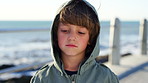Sad, face or boy at beach with wind, holiday disappointment and past memory on weekend break. Travel, reflection or child at sea with breeze, weather frustration and outdoor nostalgia in Australia.