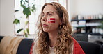 Woman, watching tv and popcorn for soccer on couch with eating, face painting and Norway flag on skin. Person, streaming and snack on sofa with broadcast for international sports competition in house