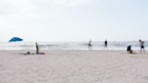 Travel, summer and blur of people on beach for vacation, holiday destination and weekend trip. Space, nature and crowd by ocean, waves and seaside for tourist location, relax and tropical adventure