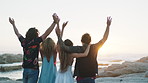 Friends, hands up and celebration at sunset by ocean, back and hug on summer vacation at seaside. People, group and embrace at beach with view for memory, bonding and connection for holiday getaway