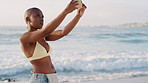 Black woman, phone and photo at beach on vacation for memory with waves, sky and post on web. African girl, photography and smartphone with mobile app, shooting or space on seaside holiday in summer