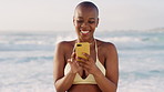Black woman, phone and laugh with texting at beach for contact, typing or meme on summer vacation. Person, smartphone and bikini with mobile app, notification and social network on holiday at seaside