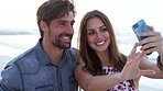 Outdoor, couple and happy on beach for selfie, travel and relationship status on social media or web. Ocean, influencer and people with smile on summer vacation, photography and laugh with partner