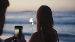 Sunset, photo and couple with sparklers on beach for celebration, new years eve and summer vacation. Dating, love and man with woman with picture for holiday, bonding and memory together by ocean