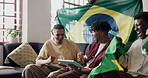 Tablet, friends and celebrate in apartment for sports game, applause or cheering with Brazil flag. Technology, watch match or win with men, high five or fist pump for national team with excited fans