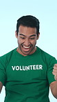 Excited, volunteer and man with fist pump for celebration, community service and successful outreach. Studio, blue background and person with smile for achievement, cheering and social responsibility