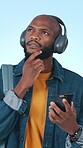 Student, thinking and man with smartphone, texting and chat with contact for scholarship opportunity. Blue background, education and black person with headphones for music and reflection in studio