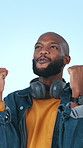 Celebration, smile and black man in studio, fist pump and cheering on blue background. Headphones, excited and African person with facial expression, wow and winner with success, omg and announcement