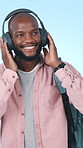 Headphones, student and black man in studio with music for positivity, good mood and relax on weekend. Happy, streaming and person listening to audio, radio and playlist for energy on blue background