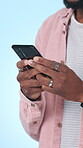 Student, education and hands with smartphone in studio, online and communication with contact on web. Blue background, learning and person with mobile for message, texting or chatting on social media