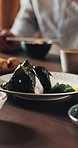 Hands, sushi and people in home, lunch and seafood for healthy meal, nutrition and wellness. Apartment, family and plate for rice, dinner and Asian cuisine with dumplings, diet and eating together