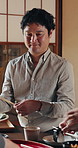 Serving, food and man in dining room with family for feast, healthy meal or Japanese cuisine in house. Hungry person, sushi and smile in home for diet, nutrition and share lunch with chopsticks