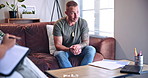 Psychology, speaking and therapy with man on sofa for communication, healing or rehabilitation. Clipboard, counselling and notes with patient talking to therapist in session for support or wellness