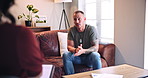 Talking, therapy and man with stress on sofa for trauma, anxiety or guidance in office appointment. Psychologist, counseling session and person with depression, mental health crisis or rehabilitation