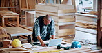 Carpentry, documents and laptop with black man in factory for manufacturing, planning or production. Computer, paperwork and reading with African person in woodworking plant for checklist review