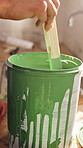 Hand, mix and paint can with person in apartment for diy project or home improvement. Maintenance, painting and stir with homeowner woman closeup in house for development or property renovation