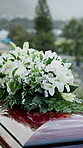 Coffin, flowers and funeral in cemetery with burial ceremony, remembrance or death for final goodbye. Casket, floral bouquet and memorial service in graveyard outdoor with honor, tribute or tradition