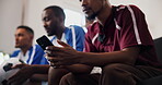 Friends, watching tv and man with phone in home for research, soccer player stats and sports betting. Below, typing and people with football match broadcast, mobile and line up news on social media