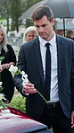 Sad, man or white rose on coffin at funeral for grief, mourning death or final goodbye in cemetery. Family, person and flower on casket at burial service for farewell, bereavement or respect at grave