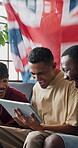Soccer game, flag and friends in house with tablet, goal celebration or live stream of sports tournament. Excitement, men or fans on sofa with tech, score victory or football subscription in England.