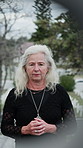Elderly, woman and praying with hope in cemetery for grief, farewell or memorial service. Senior, female person or faith with respect, loss or condolences for death, burial or ceremony in graveyard